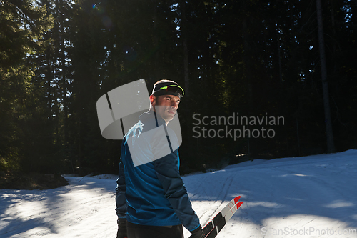 Image of Portrait handsome male athlete with cross country skis in hands and goggles, training in snowy forest. Healthy winter lifestyle concept.