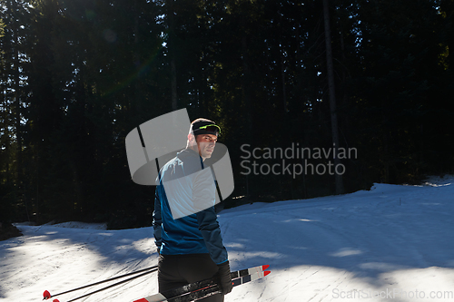 Image of Portrait handsome male athlete with cross country skis in hands and goggles, training in snowy forest. Healthy winter lifestyle concept.