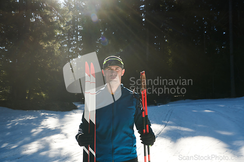Image of Portrait handsome male athlete with cross country skis in hands and goggles, training in snowy forest. Healthy winter lifestyle concept.