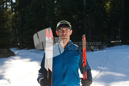 Image of Portrait handsome male athlete with cross country skis in hands and goggles, training in snowy forest. Healthy winter lifestyle concept.