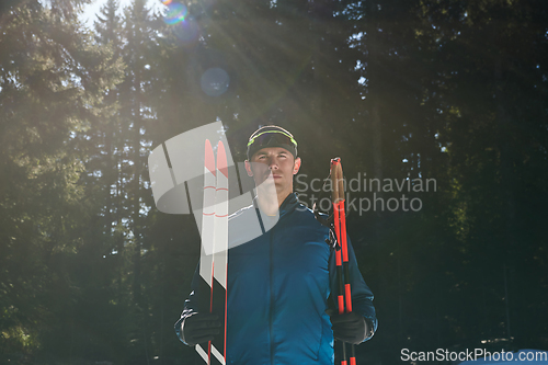 Image of Portrait handsome male athlete with cross country skis in hands and goggles, training in snowy forest. Healthy winter lifestyle concept.