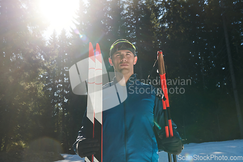 Image of Portrait handsome male athlete with cross country skis in hands and goggles, training in snowy forest. Healthy winter lifestyle concept.