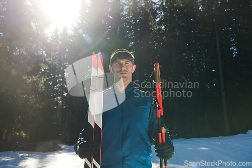 Image of Portrait handsome male athlete with cross country skis in hands and goggles, training in snowy forest. Healthy winter lifestyle concept.