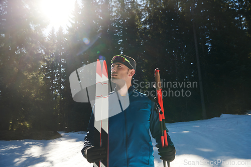 Image of Portrait handsome male athlete with cross country skis in hands and goggles, training in snowy forest. Healthy winter lifestyle concept.