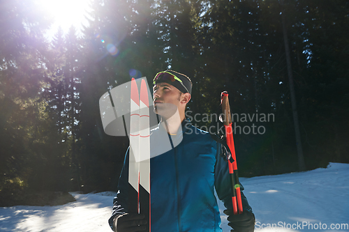 Image of Portrait handsome male athlete with cross country skis in hands and goggles, training in snowy forest. Healthy winter lifestyle concept.