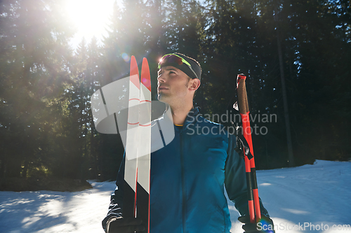 Image of Portrait handsome male athlete with cross country skis in hands and goggles, training in snowy forest. Healthy winter lifestyle concept.