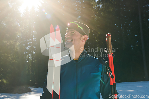 Image of Portrait handsome male athlete with cross country skis in hands and goggles, training in snowy forest. Healthy winter lifestyle concept.