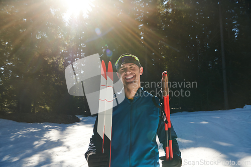 Image of Portrait handsome male athlete with cross country skis in hands and goggles, training in snowy forest. Healthy winter lifestyle concept.