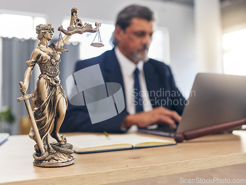 Image of Justice, statue and man in office with laptop at law firm desk, online research for court advice and senior lawyer. Judge, attorney or legal consultant in human rights, computer and internet search.