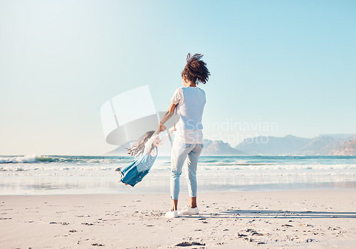 Image of Mother, spin and a child happy at the beach while on a family vacation, holiday or adventure. A young woman or mom and girl kid playing together while outdoor for summer fun and travel in nature