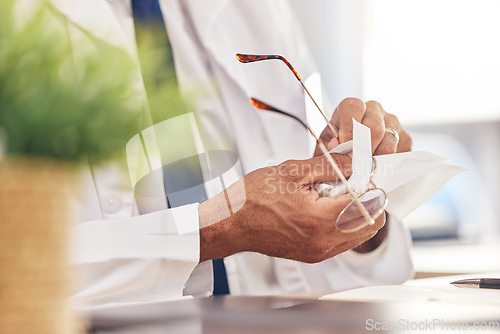 Image of Hands, healthcare and an optometrist cleaning glasses in his office for vision, eyesight or hygiene. Medical, prescription and frame lenses with a medicine professional holding eyewear in an office