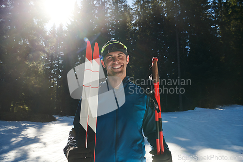 Image of Portrait handsome male athlete with cross country skis in hands and goggles, training in snowy forest. Healthy winter lifestyle concept.