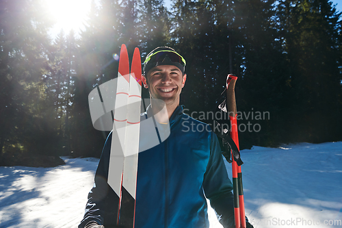 Image of Portrait handsome male athlete with cross country skis in hands and goggles, training in snowy forest. Healthy winter lifestyle concept.