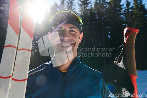 Image of Portrait handsome male athlete with cross country skis in hands and goggles, training in snowy forest. Healthy winter lifestyle concept.