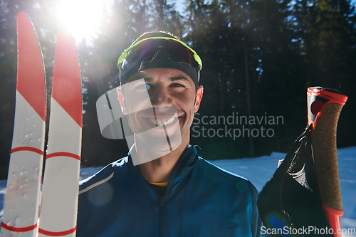 Image of Portrait handsome male athlete with cross country skis in hands and goggles, training in snowy forest. Healthy winter lifestyle concept.