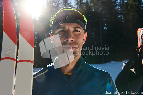 Image of Portrait handsome male athlete with cross country skis in hands and goggles, training in snowy forest. Healthy winter lifestyle concept.