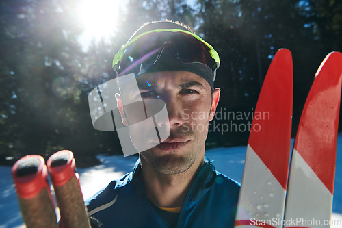 Image of Portrait handsome male athlete with cross country skis in hands and goggles, training in snowy forest. Healthy winter lifestyle concept.