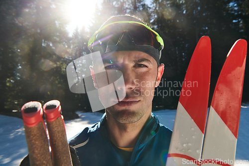 Image of Portrait handsome male athlete with cross country skis in hands and goggles, training in snowy forest. Healthy winter lifestyle concept.