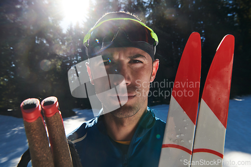 Image of Portrait handsome male athlete with cross country skis in hands and goggles, training in snowy forest. Healthy winter lifestyle concept.