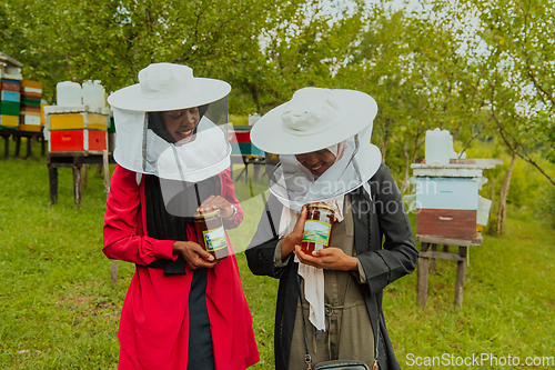 Image of Portrait of an Arab investors holding a jar of honey in their hands while standing in front of a large honey farm. The concept of investing in small businesses