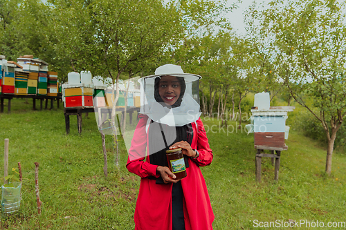 Image of Portrait of a Muslim investitor in the beekeeping department of a honey farm holding a jar of honey in her hand