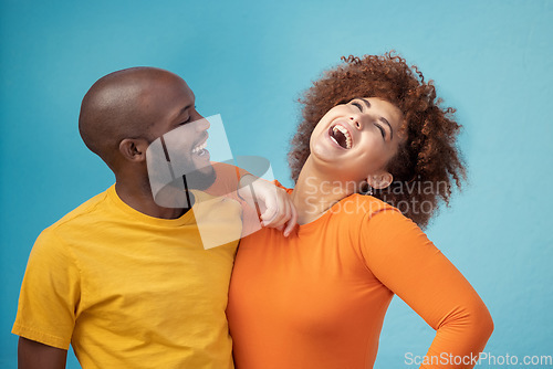 Image of Love, laughing and interracial couple with a joke isolated on a blue background in a studio. Comic, funny and black man and woman smiling with happiness, care and confidence on a backdrop together