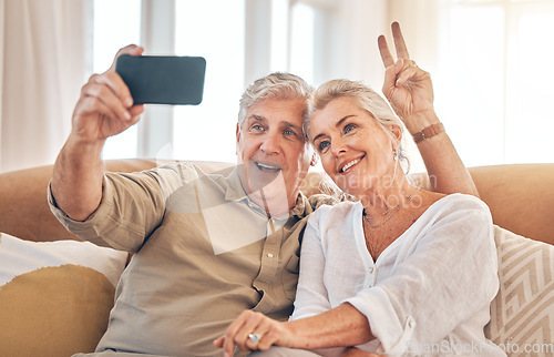 Image of Happy senior couple, peace sign and selfie in relax on living room sofa for photograph, memory or vlog at home. Elderly man and woman smile for picture, photo or social media on lounge couch together