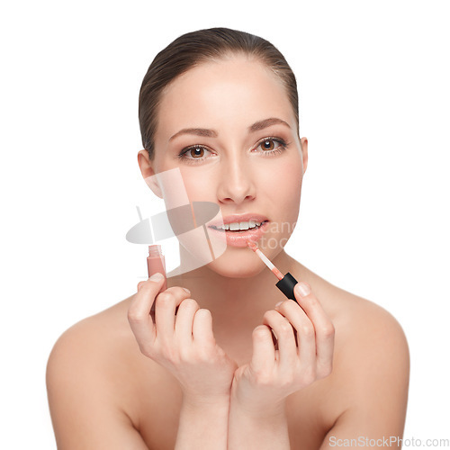 Image of Giving her lips that extra touch. Studio portrait of a beautiful brunette applying lip gloss.