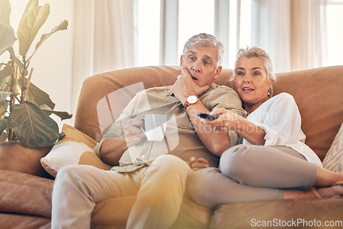 Image of Senior couple, watching tv and sofa in relax for streaming, movie or series in living room at home. Elderly man and woman with coffee and remote together for changing channel and online entertainment