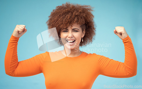 Image of Portrait, strong and bicep with a black woman in studio on a blue background flexing her muscle for empowerment. Face, equality and power with an attractive young female posing to promote health