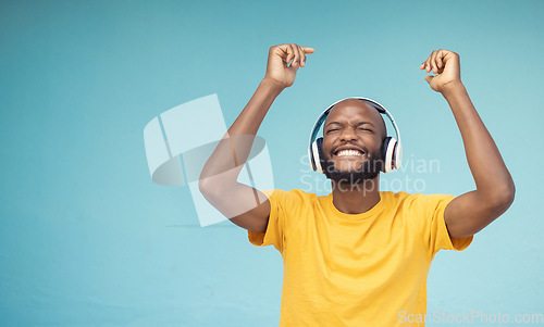 Image of Music, dance and mockup with a black man in studio on a blue background wearing headphones. Radio, freedom and fun with a male dancing indoor alone while streaming an online audio playslist