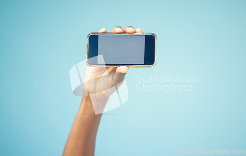 Image of Phone, mockup screen and man hand advertising sale, promotion or brand on website or internet. Person with smartphone in hand on blue background studio for contact us, online contact or connection