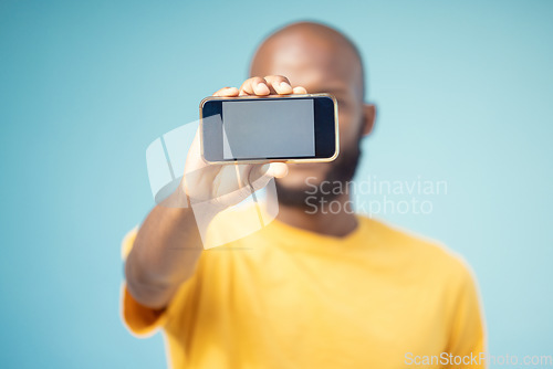 Image of Mockup screen, phone and black man advertising sale, promotion or brand on website or internet. Person with smartphone in hand on blue background studio for contact us, online contact or connection