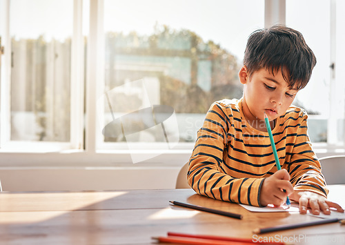 Image of Drawing, education and a child in a house at a table for art, learning writing or creativity. Serious, morning and a kid with paper and color at a desk in a home for knowledge, studying or a picture