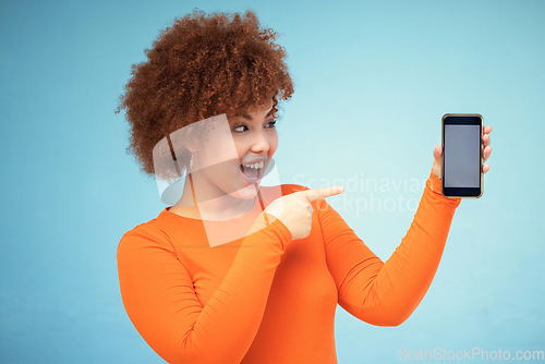 Image of Woman, excited and phone mockup screen advertising sale, promotion or brand on website or internet. Person pointing hand at smartphone on blue background studio for about us or online winning deal