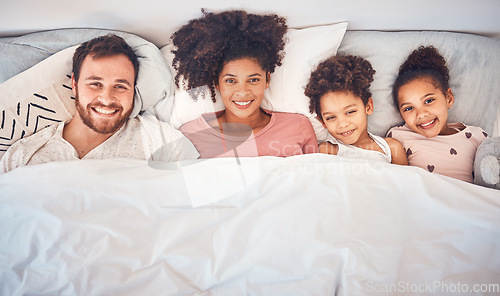 Image of Family, happy and portrait in bed at home for quality time, bonding or morning routine. Above, mixed race and smile of a man, woman and children together in a bedroom with love, care and comfort