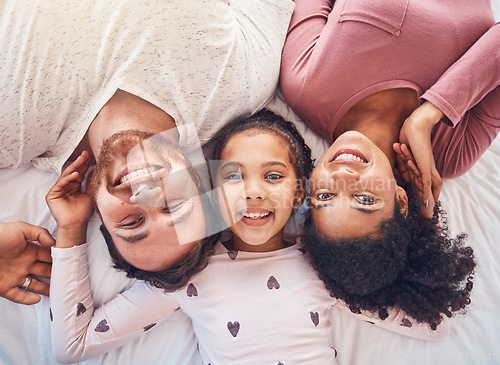 Image of Happy family, smile and portrait on bed at home for quality time, bonding or morning routine. Above, mixed race and face of a man, woman and girl kid together in a bedroom with love, care and comfort