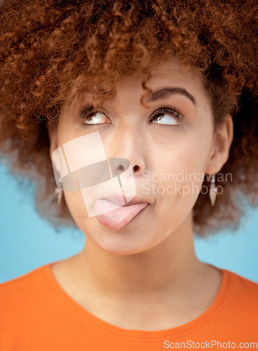 Image of Comic, tongue and face with a black woman in studio on a blue background feeling funny or silly. Comedy, joke and humor with an attractive young female looking goofy while posing alone indoor