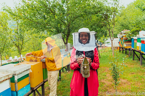 Image of Portrait of a Muslim African American woman in the beekeeping department of a honey farm holding a jar of honey in her hand