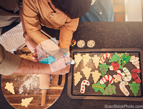 Image of Christmas, above and a family baking cookies, help with food and process of decoration. Hands, child and teamwork for icing sweet dessert or biscuits for a festive holiday in the kitchen together