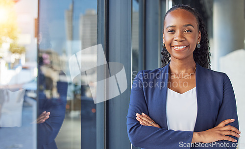 Image of Portrait, window and arms crossed with a business black woman standing in her professional office. Smile, corporate leadership with a happy female manager or boss in the workplace for empowerment