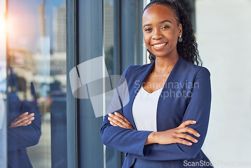 Image of Portrait, window and arms crossed with a business woman standing in her professional office. Smile, corporate leadership with a happy african manager or boss in the workplace for empowerment