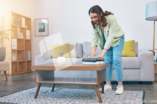 Image of Woman, home and laundry on living room table for hygiene, cleaning and folding for housework in morning. Girl, fabric and cotton towel on desk for organized house, thinking and routine in apartment