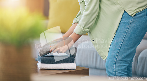 Image of Hands, home and fold laundry on table for hygiene, cleaning and soft clothes for housework in living room. Woman, fabric and cotton towel on desk for organized house, service and routine in apartment