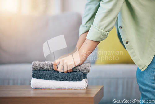 Image of Hands, home and laundry on living room table for hygiene, cleaning and folding for housework in morning. Woman, fabric and cotton towel on desk for organized house, service and routine in apartment