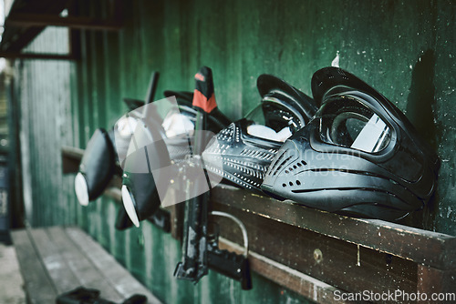 Image of Paintball, helmet and guns on rack at station of sports gear waiting for match, competition or war battle. Paint balling sportswear, weapon or safe equipment on shelf ready for game, fight or warfare