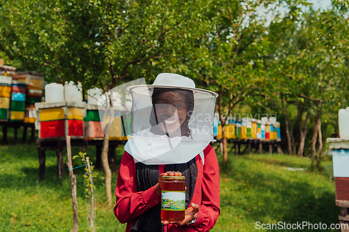 Image of Portrait of Arab investitor in the beekeeping department of a honey farm holding a jar of honey in her hand