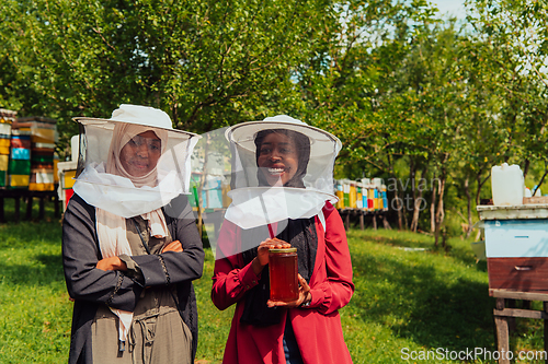 Image of Portrait of a Arab investitors in the beekeeping department of a honey farm holding a jar of honey in her hand