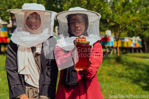 Image of Portrait of a Arab investitors in the beekeeping department of a honey farm holding a jar of honey in her hand