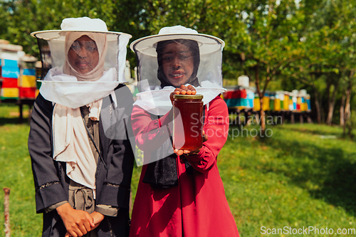 Image of Portrait of a Arab investitors in the beekeeping department of a honey farm holding a jar of honey in her hand